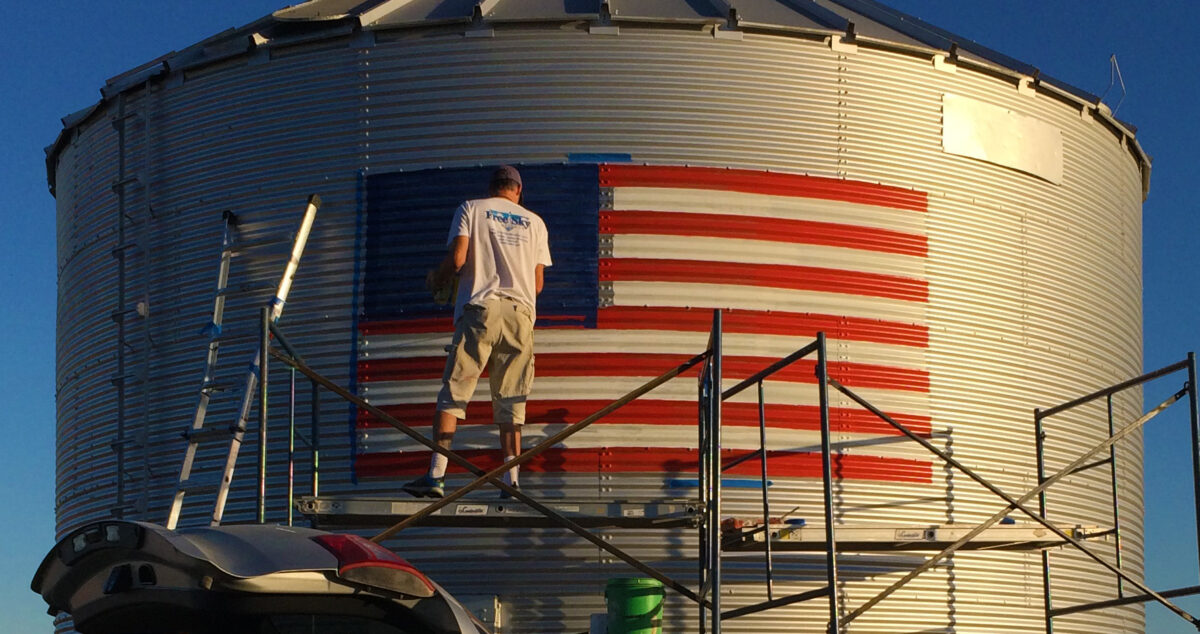 Artist painting American Flag on silo